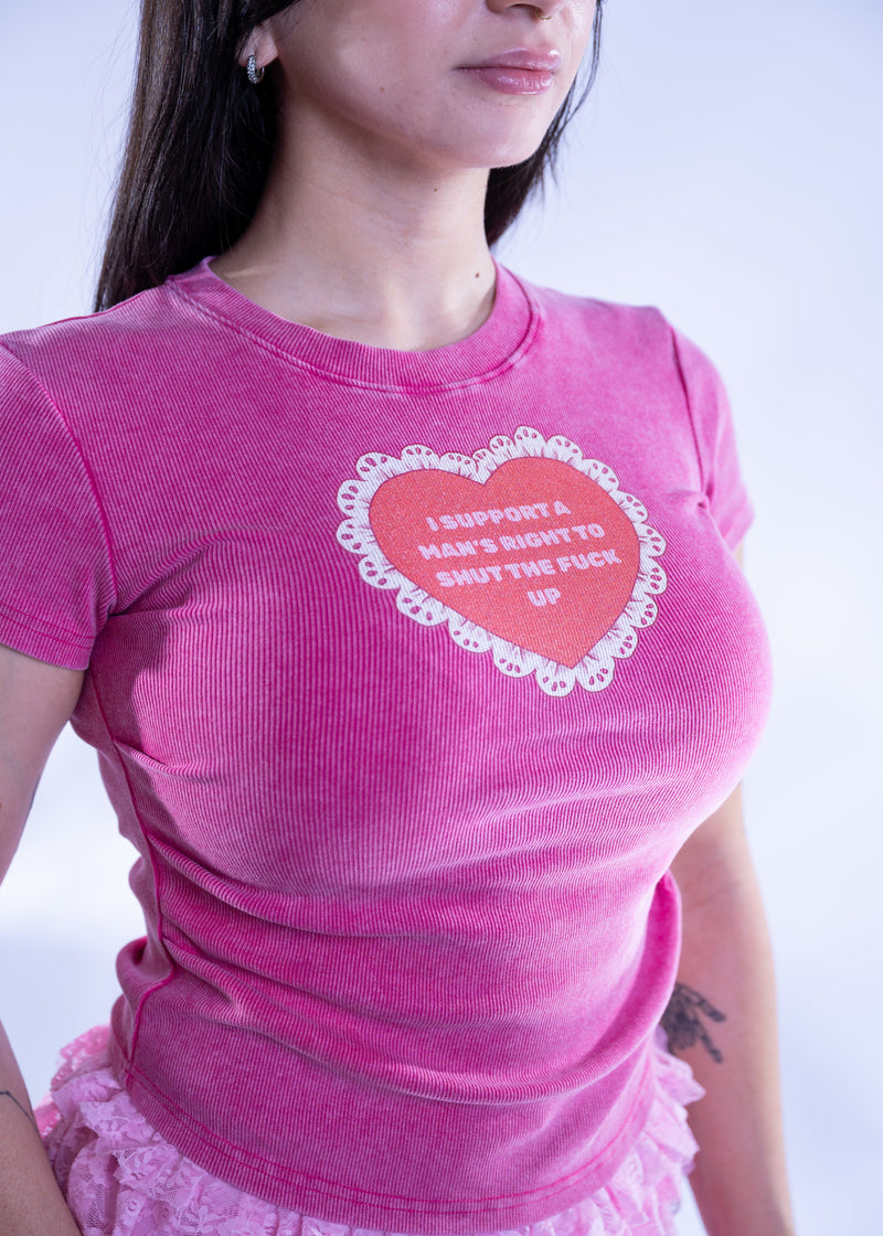 Person wearing a pink t-shirt with a heart and lace graphic design and text.