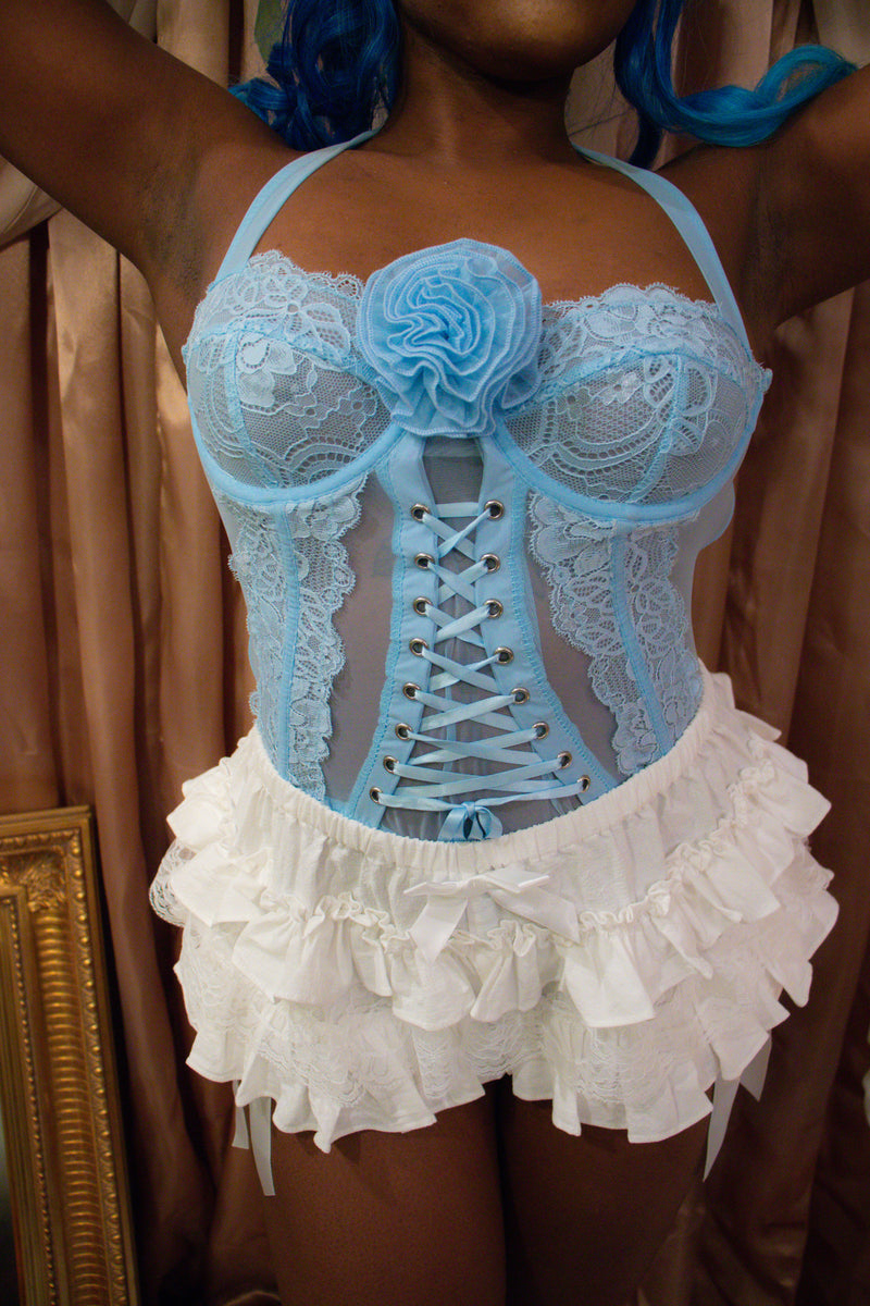 This image features an elegant Blueberry Pie Lace Corset, designed with both functionality and aesthetics in mind. The corset sports a soft blue color, adorned with intricate lace detailing and a prominent rosette at the chest, enhancing its classic appeal.