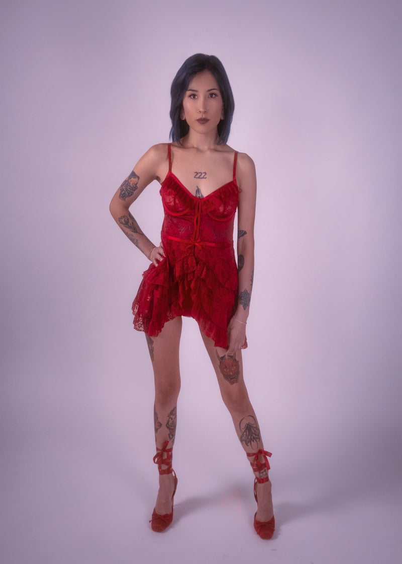 Woman wearing a red lace babydoll dress with matching high heels on a white background